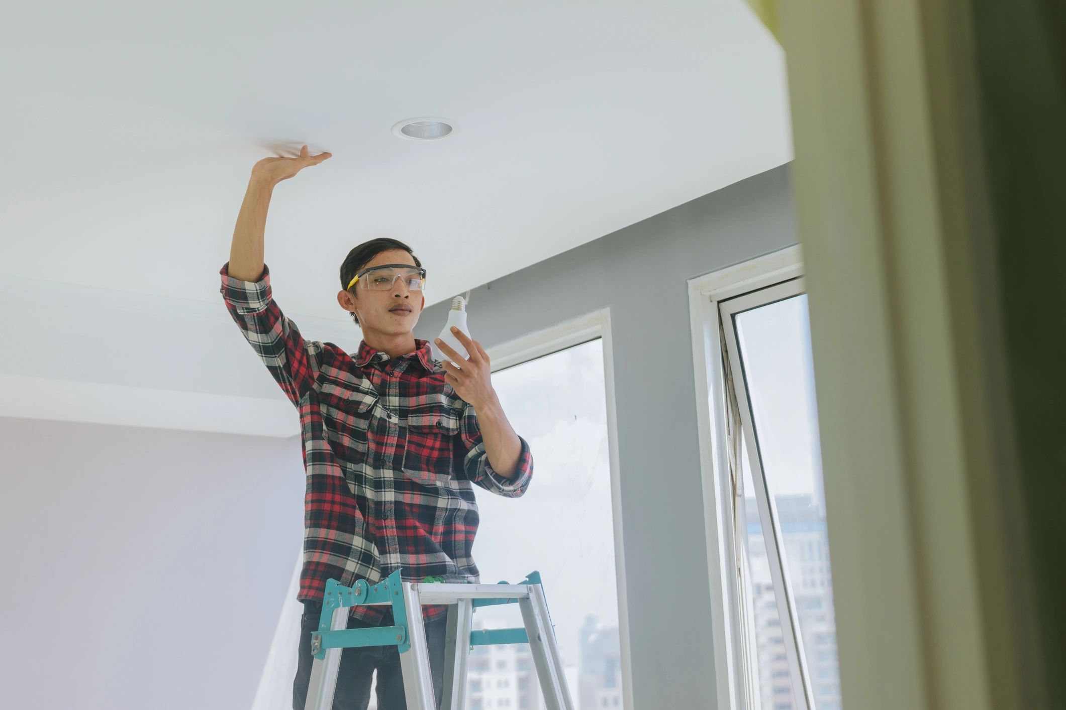 Electrician installing a ceiling light in a modern property
